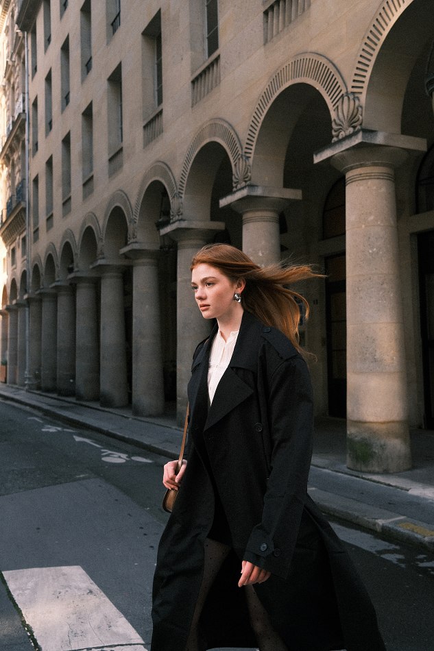 Camryn wearing a long black coat on a city street